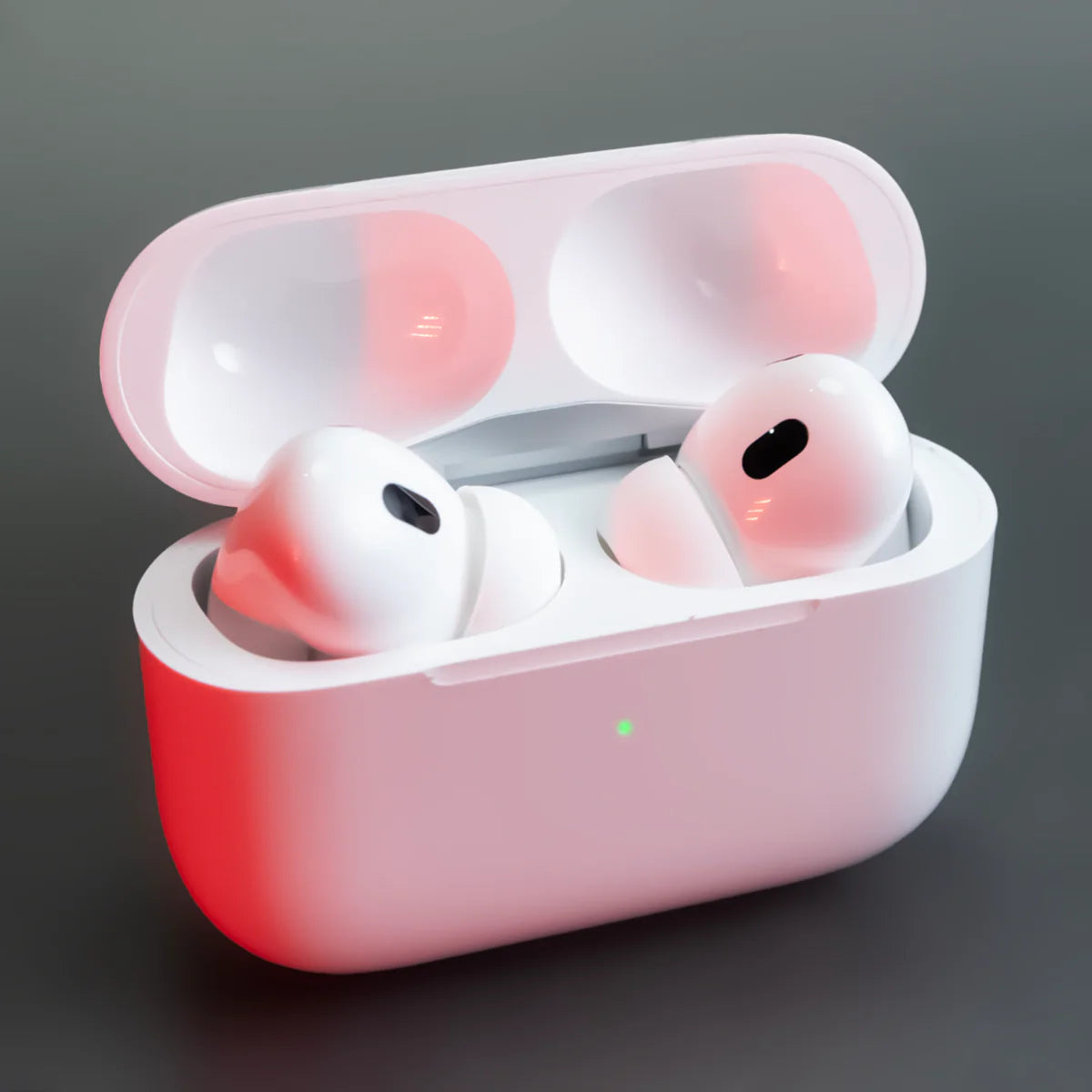 Wireless earbuds in a pink charging case on a dark background