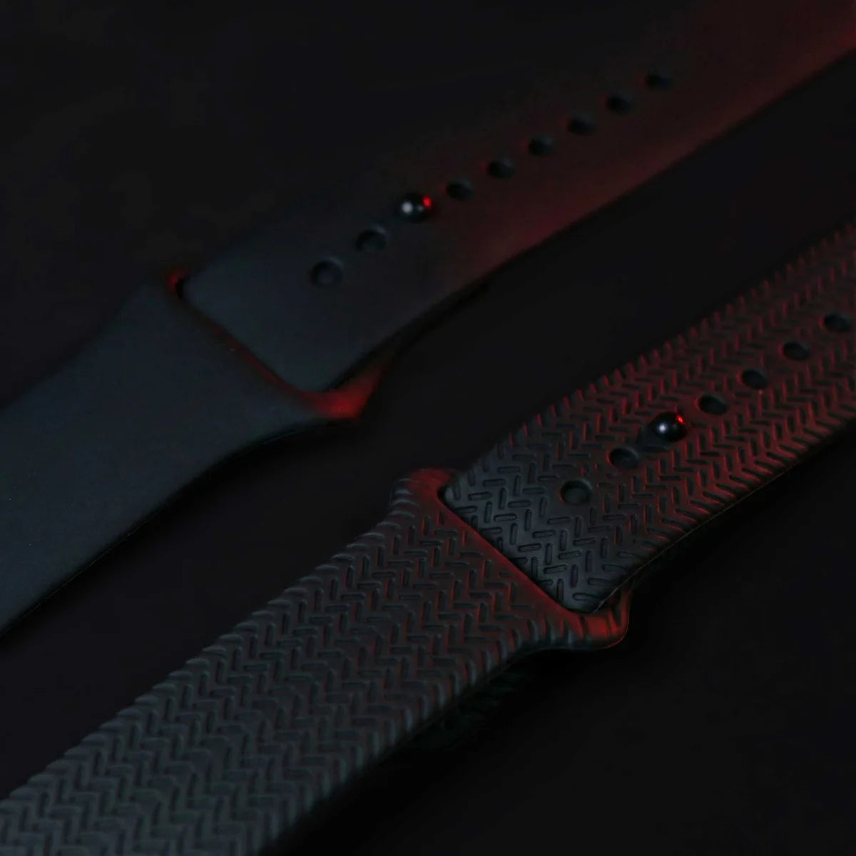 Close-up of a textured watch strap with red accents on a dark background
